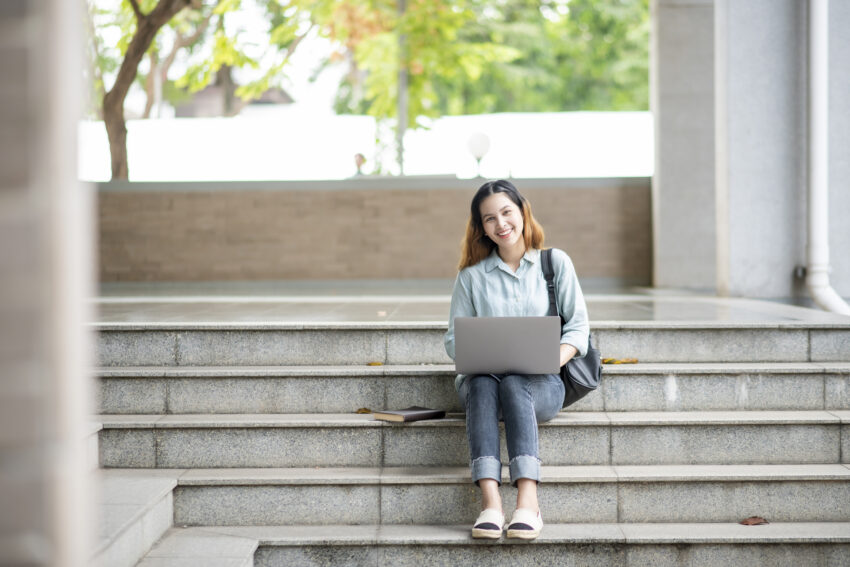 Studentka Politechniki warszawskiej siedząca na schodach z laptopem na kolanach